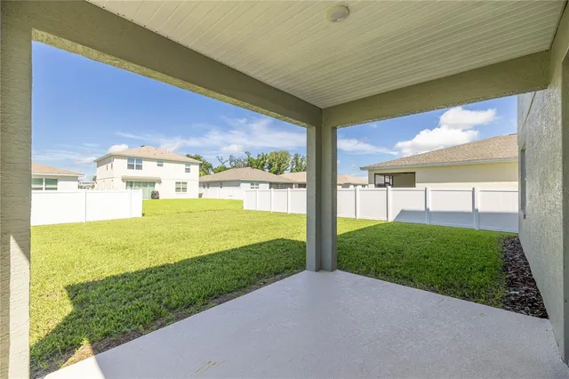a view of a white house with a big yard and potted plants