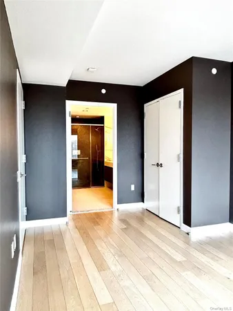 a view of a hallway with wooden floor and a bathroom