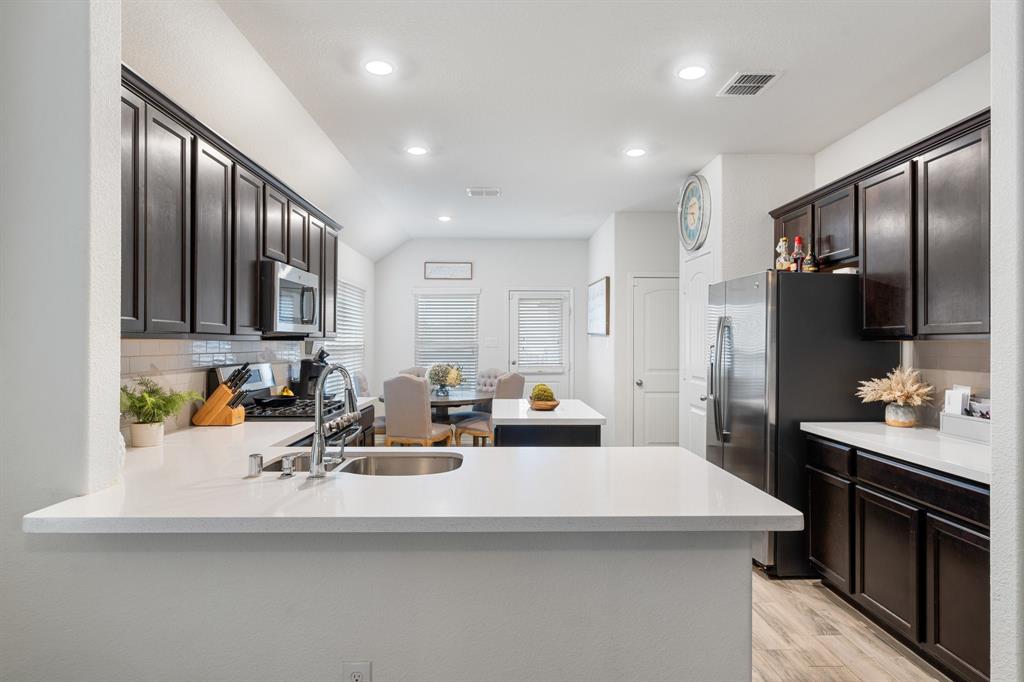1490 Alamandine Avenue Cross Roads, TX 76227 - Photo 7 of 23 a kitchen with sink a refrigerator and chairs