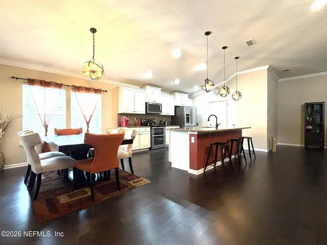 a view of a dining room and livingroom with furniture wooden floor a chandelier
