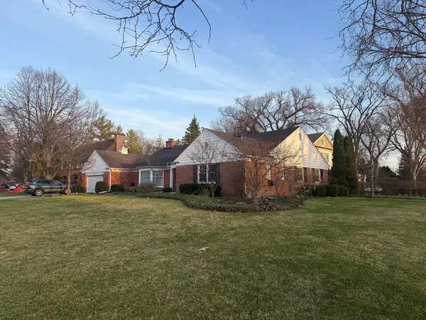 a view of a big house with a big yard and large trees