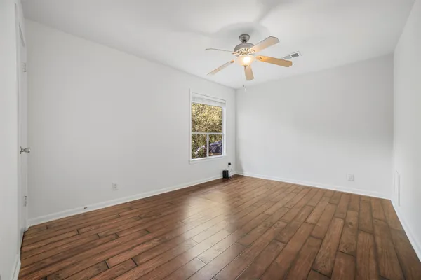 a view of an empty room with wooden floor and a window