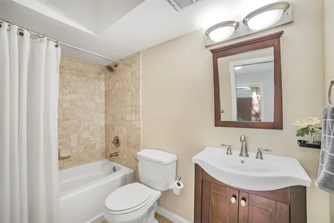 a bathroom with a sink a toilet a mirror a vanity and bathtub