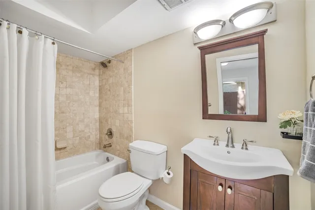 a bathroom with a sink a toilet a mirror a vanity and bathtub