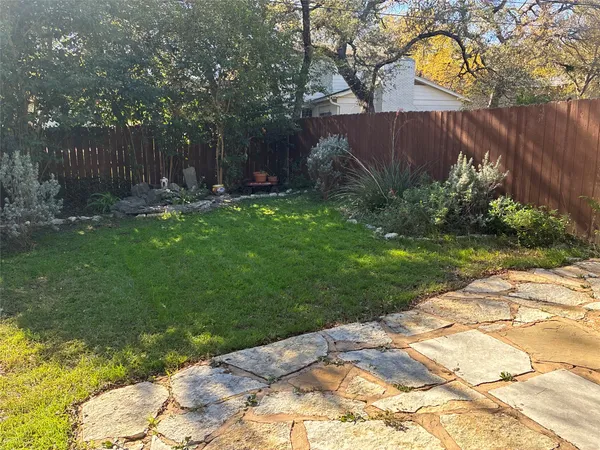 a view of backyard with wooden fence and a large tree