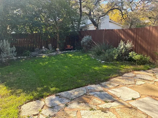 a view of backyard with table and chairs and wooden fence