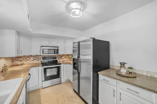 a kitchen with stainless steel appliances granite countertop a sink a stove a refrigerator and cabinets