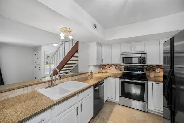 a kitchen with granite countertop a sink stainless steel appliances and cabinets