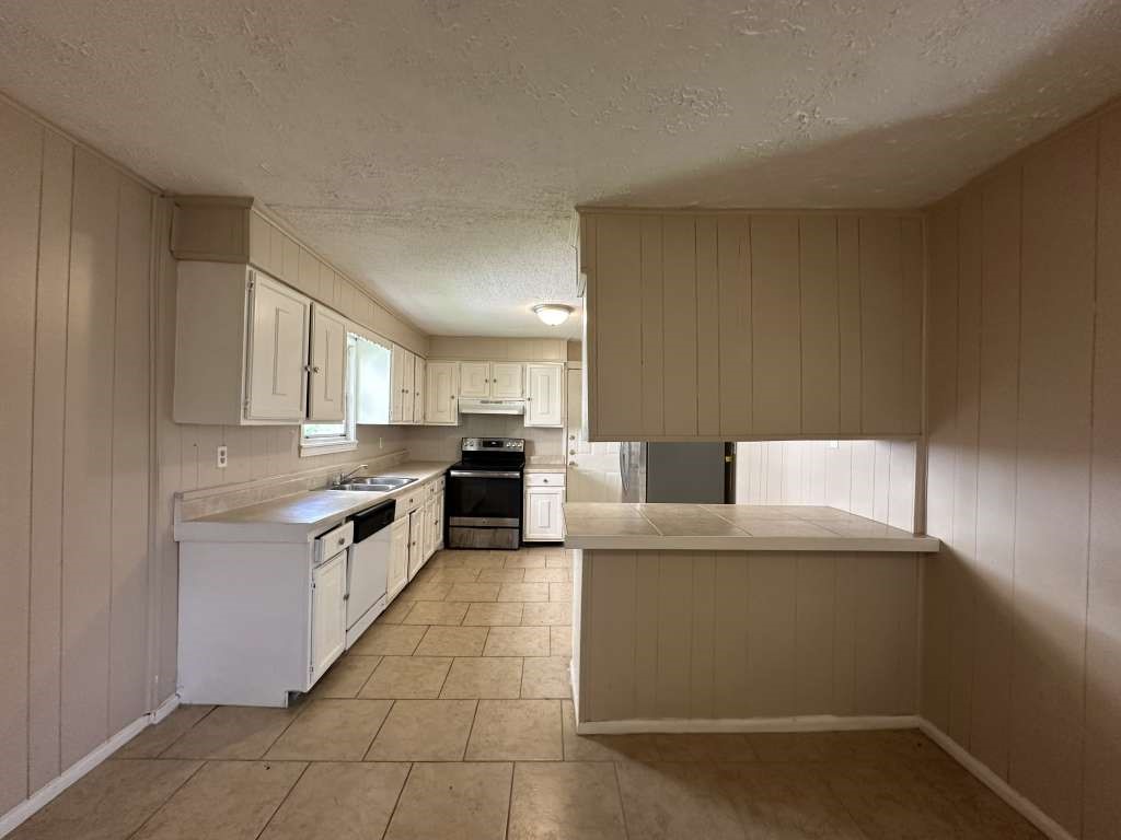 5424 San Juan Street Houston, TX 77020 - Photo 4 of 15 a kitchen with stainless steel appliances a stove a sink a refrigerator white cabinets and couches