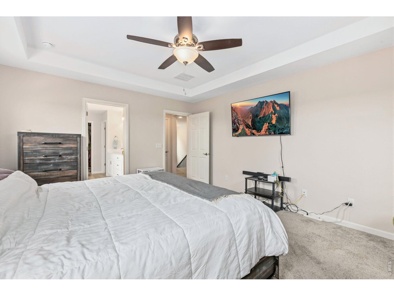 955 Rustling Street Windsor, CO 80550 - Photo 13 of 34 a bedroom with a bed a dresser and a ceiling fan