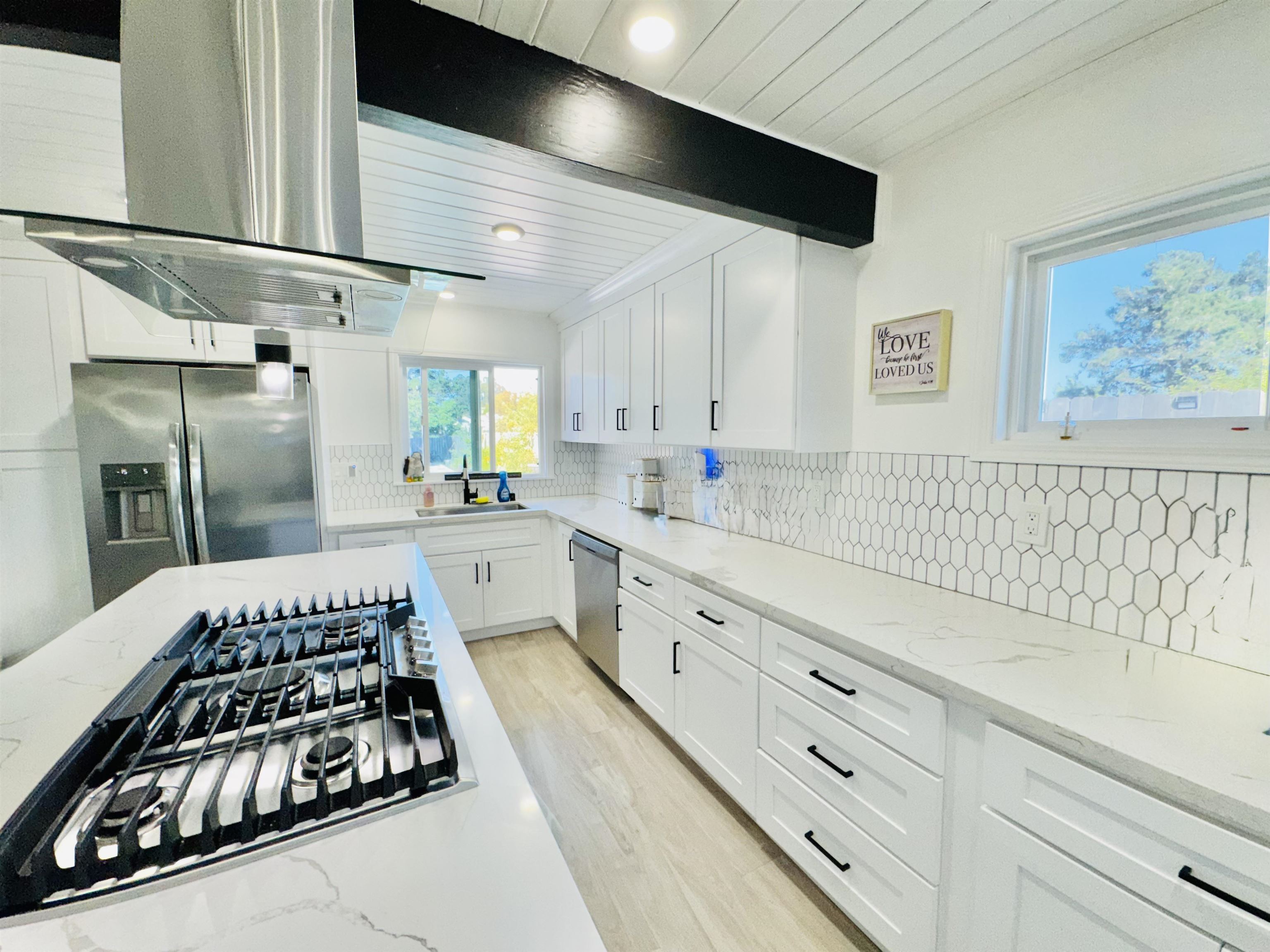 534 Rincon Road El Sobrante, CA 94803 - Photo 5 of 16 Kitchen featuring ventilation hood, stainless steel appliances, white cabinets, light stone countertops, and tasteful backsplash