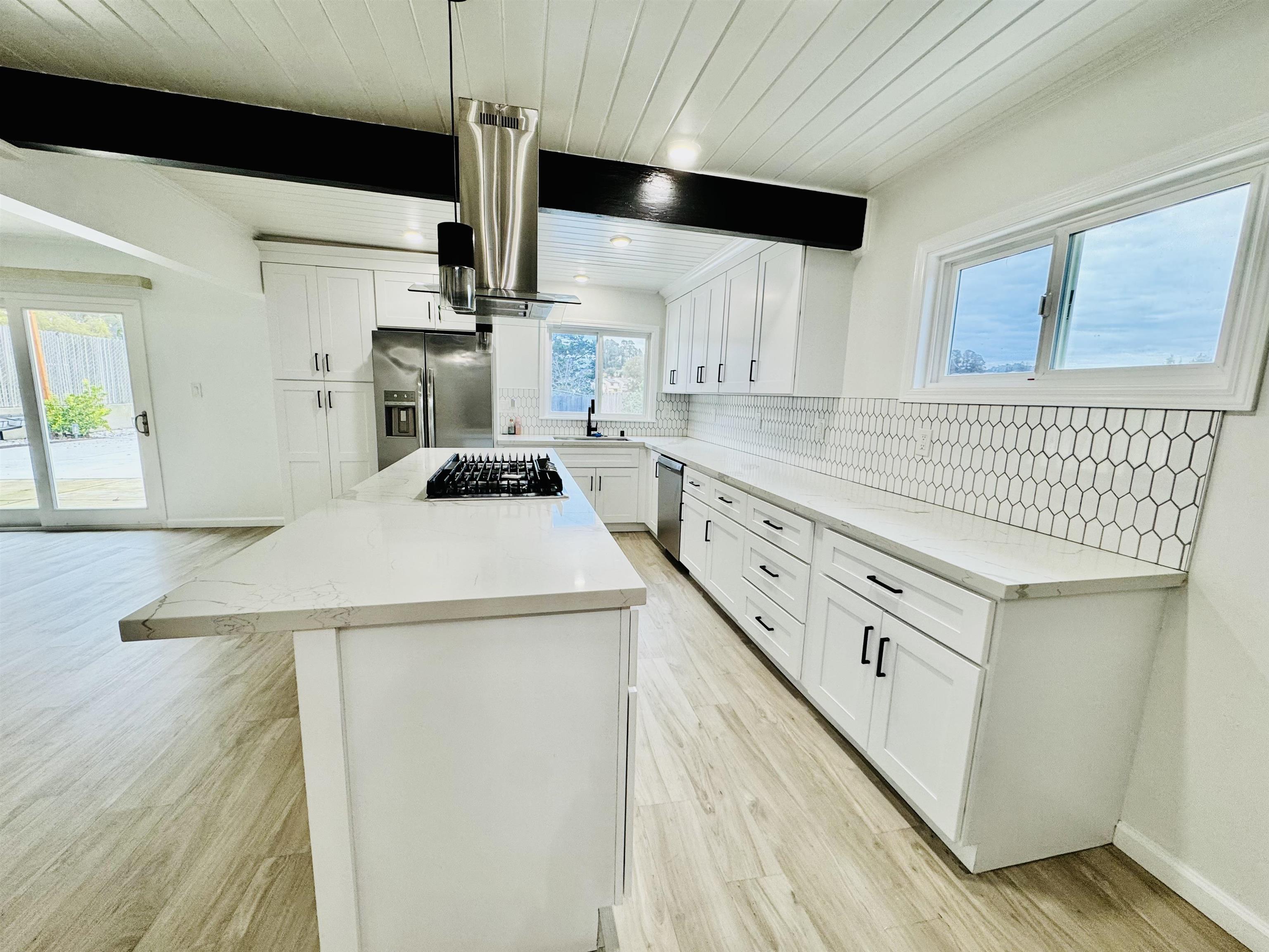 534 Rincon Road El Sobrante, CA 94803 - Photo 6 of 16 Kitchen featuring white cabinets, decorative backsplash, a center island, light stone counters, and range hood