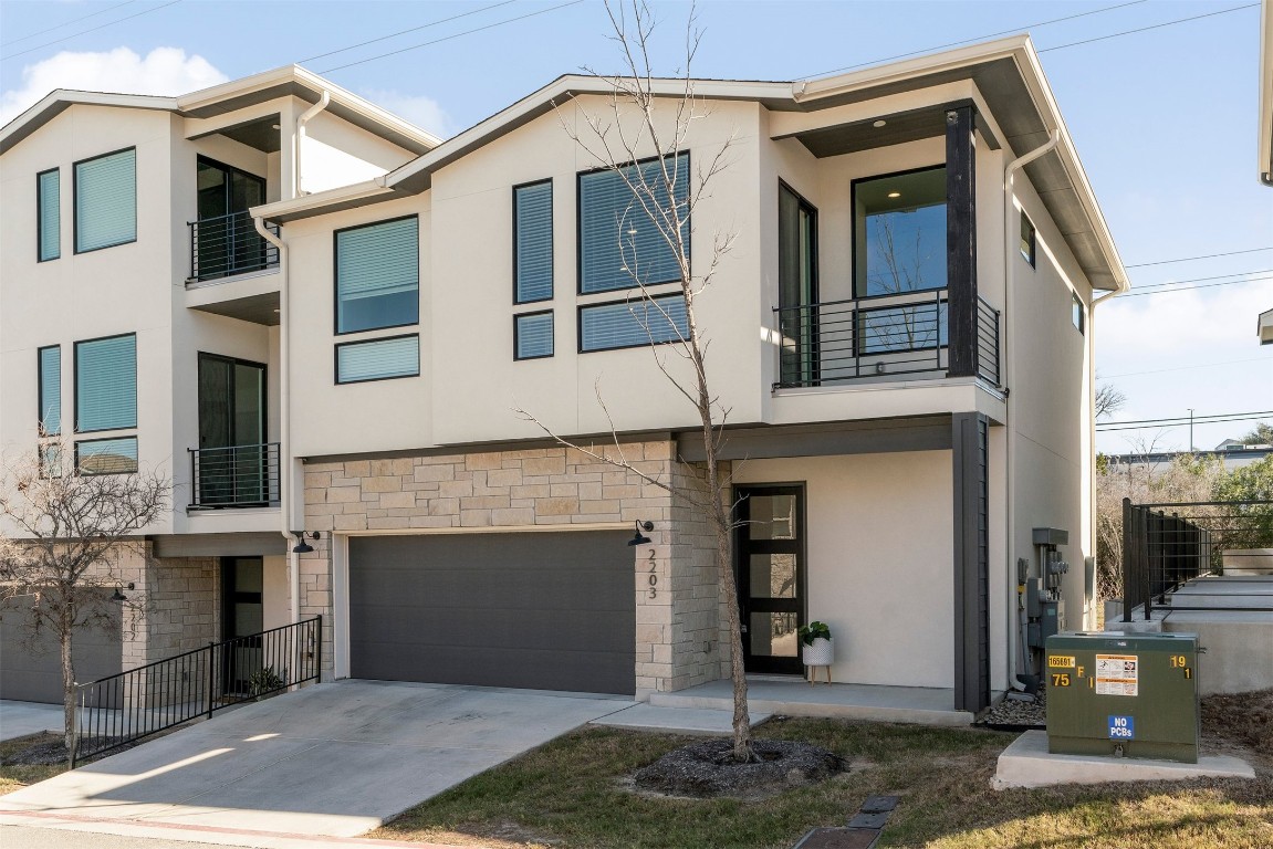 2050 Lohmans Spur Road, Unit 2203 Lakeway, TX 78734 - Photo 32 of 34 This end-unit townhome is framed by lush landscaping and a stucco and stone exterior, offering added privacy with neighbors on only one side