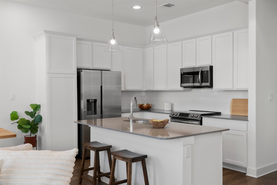 2050 Lohmans Spur Road, Unit 2203 Lakeway, TX 78734 - Photo 4 of 34 The kitchen is centered around a generous island with breakfast bar seating, creating a natural gathering spot that works for casual meals, prep space, and everyday conversation