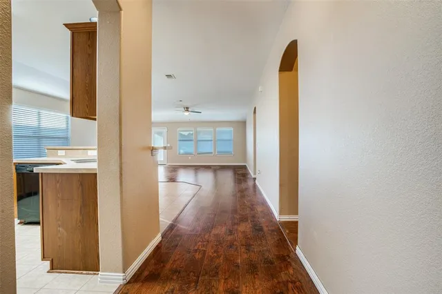 a view of a hallway with wooden floor and a bathroom