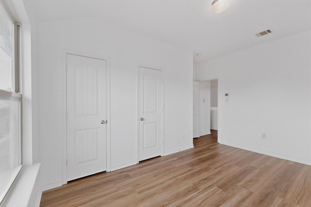 426 Harding Lane Lavon, TX 75166 - Photo 36 of 40 Room featuring wood-finish flooring, white painted walls, a white trim window, and two white paneled doors with silver hardware