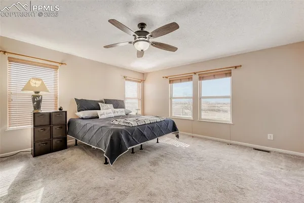 a spacious bedroom with a bed a dresser and a window