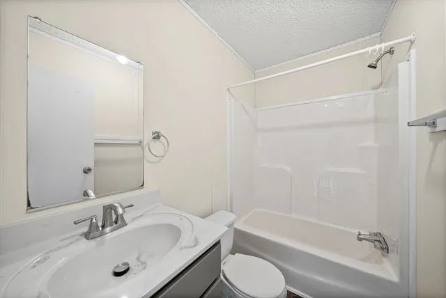 a bathroom with a bathtub shower sink vanity mirror and toilet