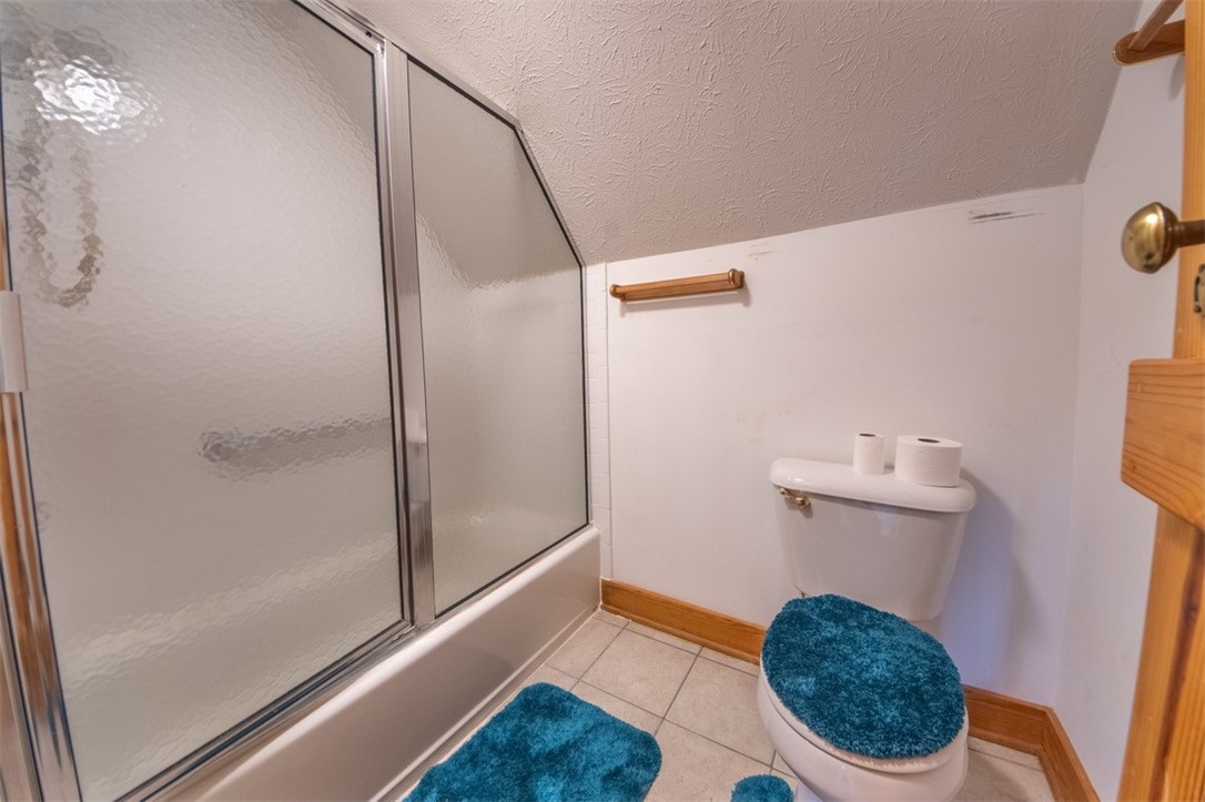 846 Twiggs Ferry Road Hartfield, VA 23071 - Photo 4 of 28 Bathroom with a textured ceiling, light tile patterned floors, combined bath / shower with glass door, and vaulted ceiling