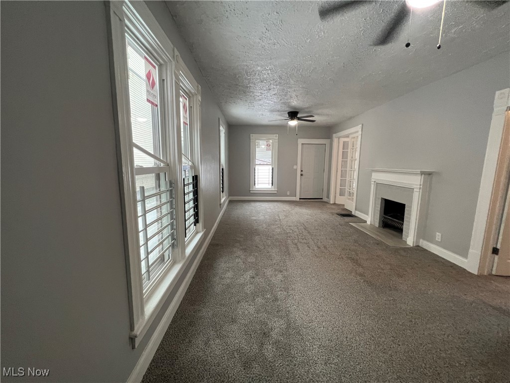 4278 Warner Road Cleveland, OH 44105 - Photo 6 of 44 Unfurnished living room featuring a ceiling fan, carpet flooring, a fireplace with flush hearth, and a textured ceiling