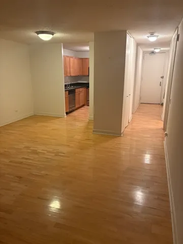 a view of kitchen and empty room with wooden floor
