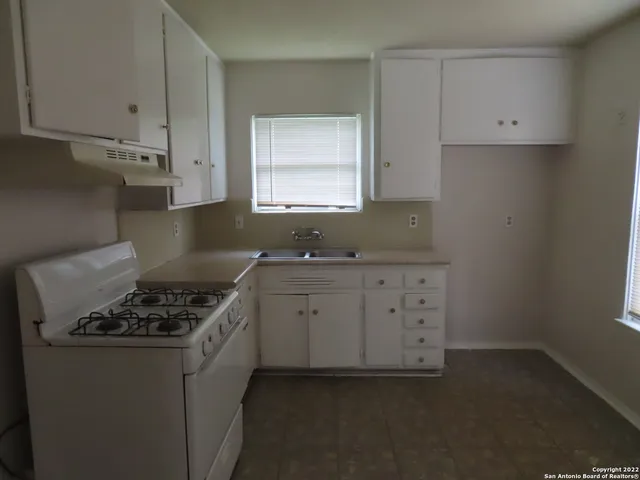 a kitchen with granite countertop a sink a stove and cabinets
