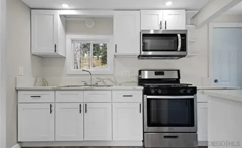 a kitchen with white cabinets and stainless steel appliances