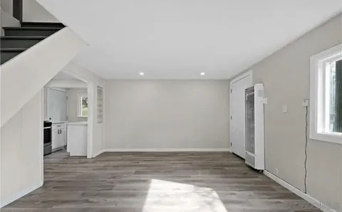 a view of empty room with wooden floor and window