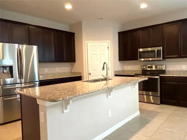 a kitchen with kitchen island a sink stove and refrigerator