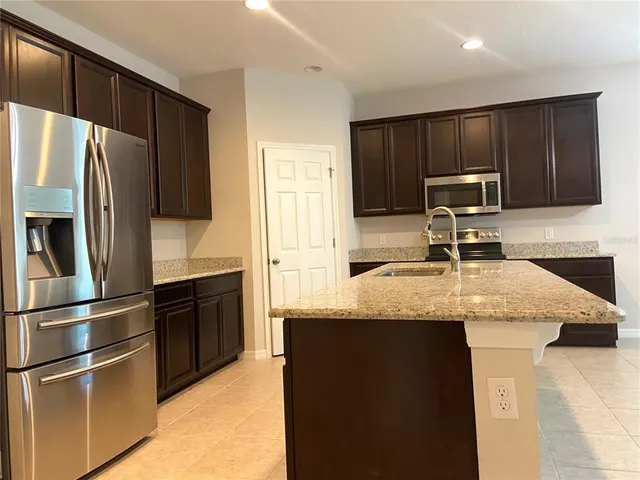 a kitchen with granite countertop a refrigerator stove and sink
