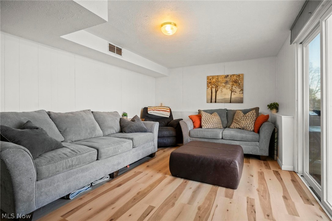 1088 Novak Road Grafton, OH 44044 - Photo 26 of 33 Living room featuring wood finished floors, a textured ceiling, and a decorative wall