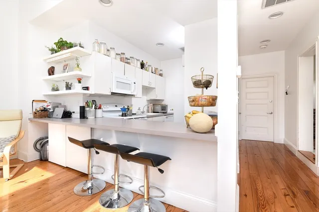 a kitchen with granite countertop a dining table chairs and white cabinets