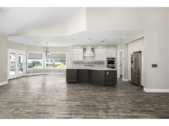 a large white kitchen with kitchen island a sink stainless steel appliances and cabinets