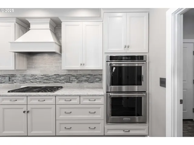 a kitchen with granite countertop white cabinets and stainless steel appliances