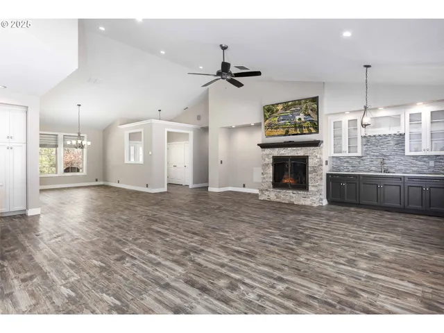 an empty room with wooden floor fireplace and windows