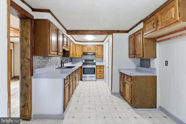 a kitchen with granite countertop a sink a stove top oven a granite counter tops and a view of living room