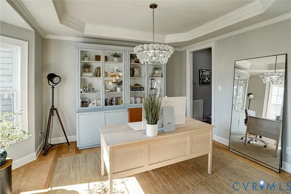 a dining room with wooden floor a chandelier a glass table and chairs