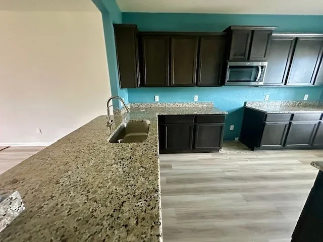 a kitchen with stainless steel appliances kitchen island granite countertop a stove and a microwave oven