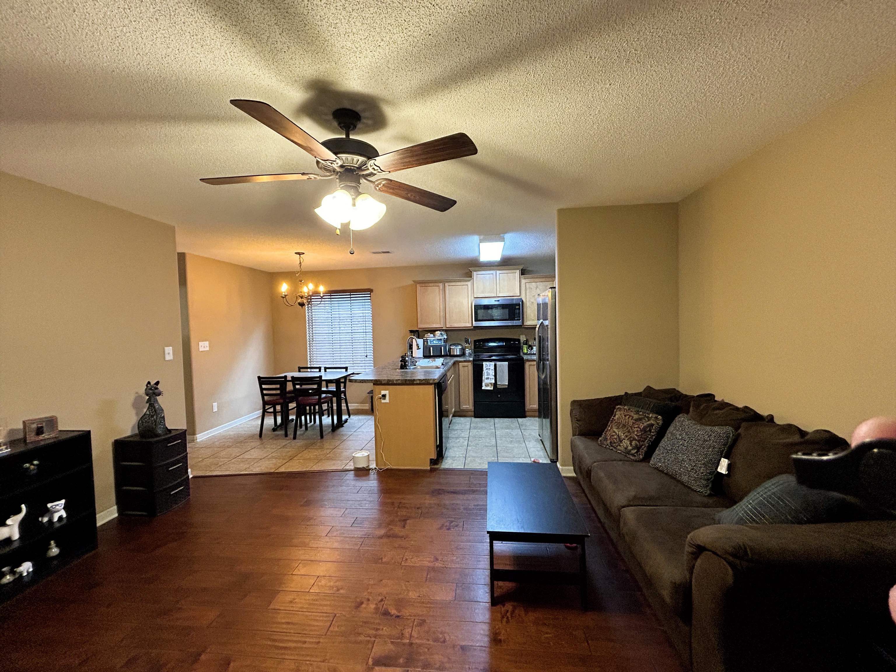 7927 Lowrance Road Memphis, TN 38125 - Photo 3 of 13 Living area with a textured ceiling, dark wood-style flooring, ceiling fan, and a chandelier