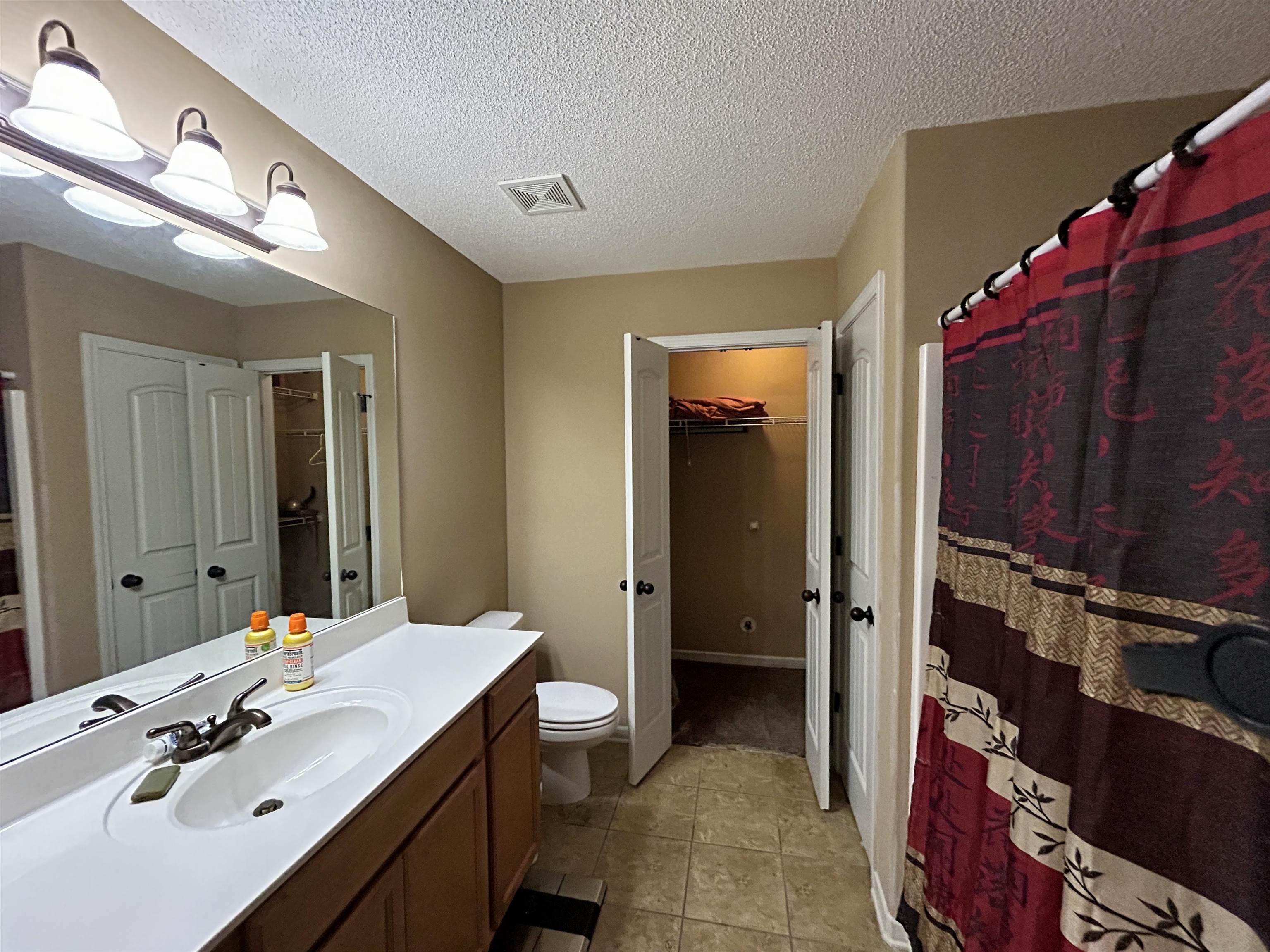 7927 Lowrance Road Memphis, TN 38125 - Photo 8 of 13 Bathroom featuring vanity, curtained shower, a spacious closet, a textured ceiling, and light tile patterned floors