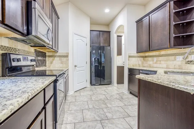 a kitchen with stainless steel appliances granite countertop a refrigerator and a sink