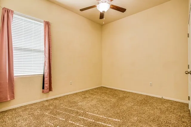 an empty room with a ceiling fan and carpet