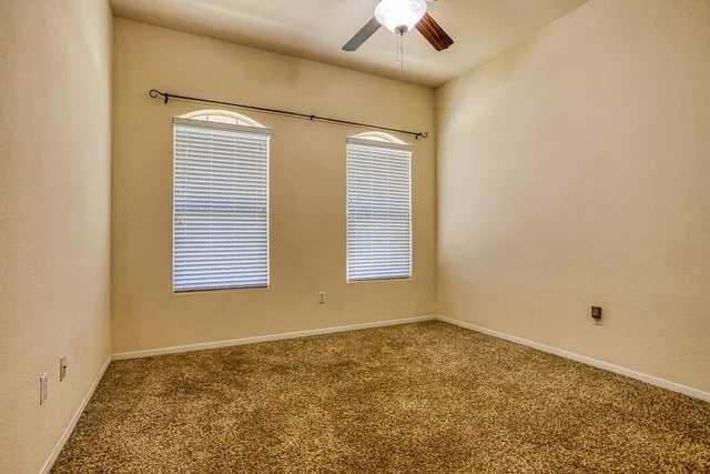 an empty room with a window and a ceiling fan