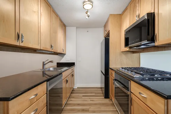 a kitchen with stainless steel appliances granite countertop a stove a sink and a microwave