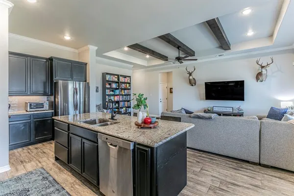 a kitchen with stainless steel appliances granite countertop a sink dishwasher stove and refrigerator with wooden floor