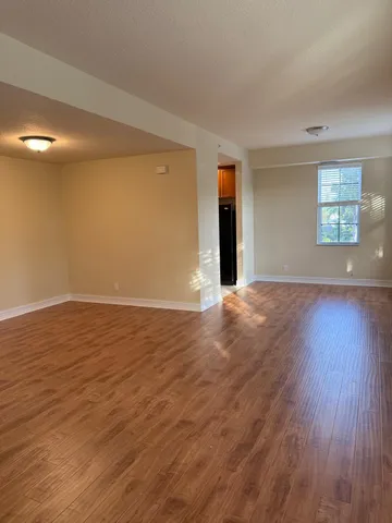 a view of an empty room with wooden floor and a window