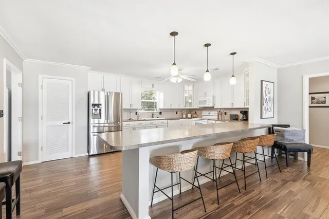 a large kitchen with cabinets wooden floor and stainless steel appliances