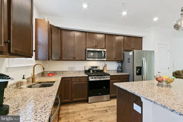 a kitchen with stainless steel appliances granite countertop a sink stove and refrigerator