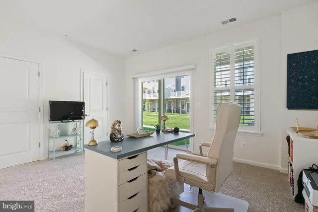 a work room with furniture a flat screen tv and a window