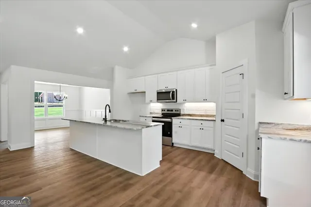 a kitchen with stainless steel appliances a stove a sink a refrigerator and white cabinets